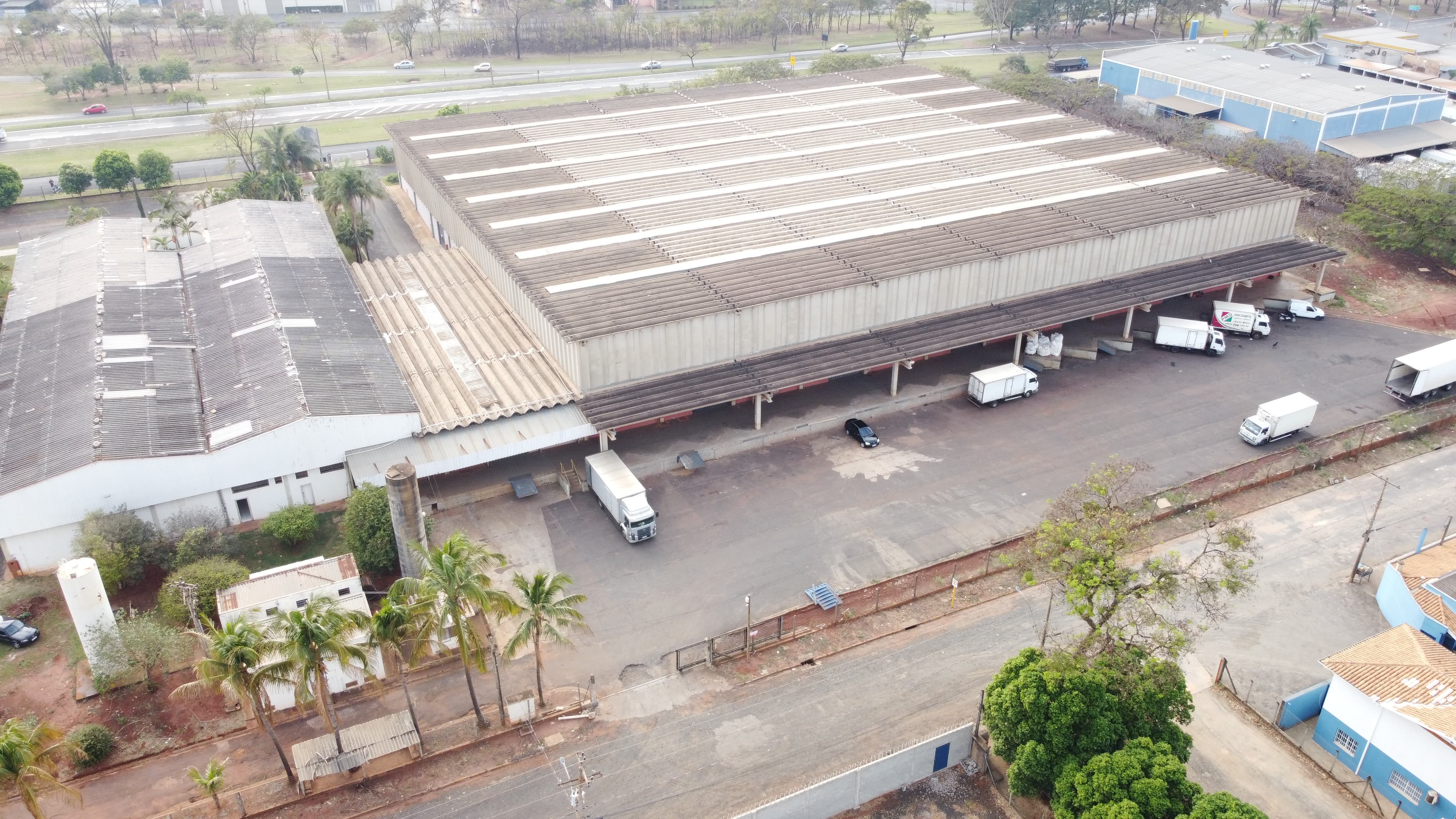Vista aérea de galpão industrial com docas e caminhões no pátio